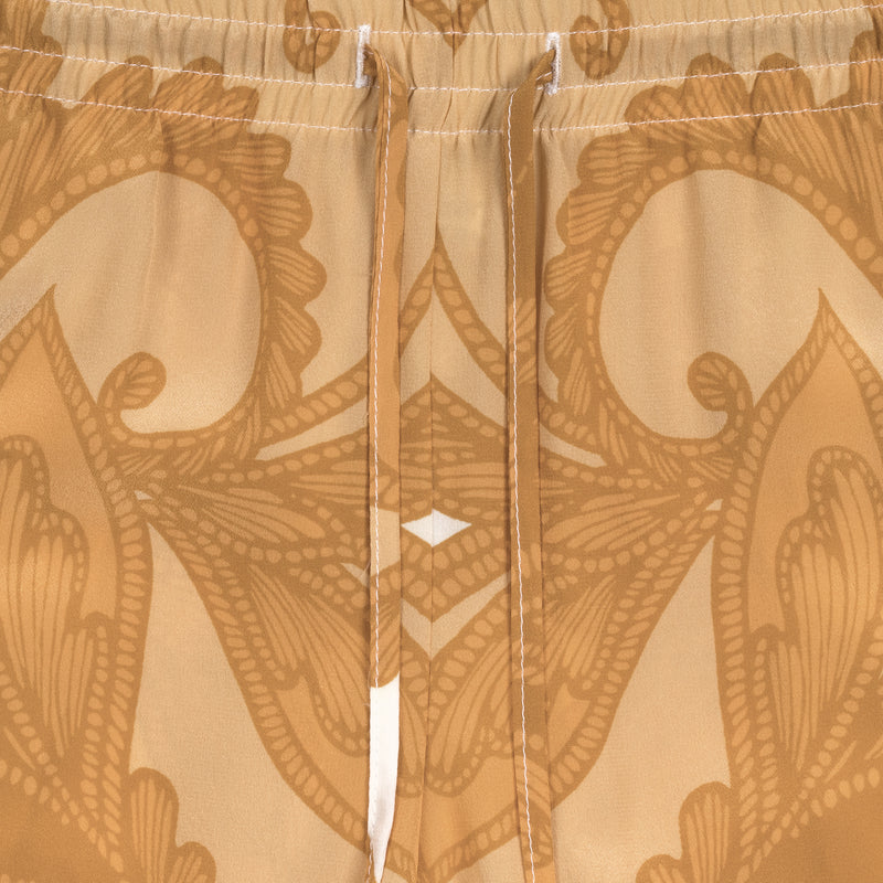 detail of a women silk pant in a yellow paisley print