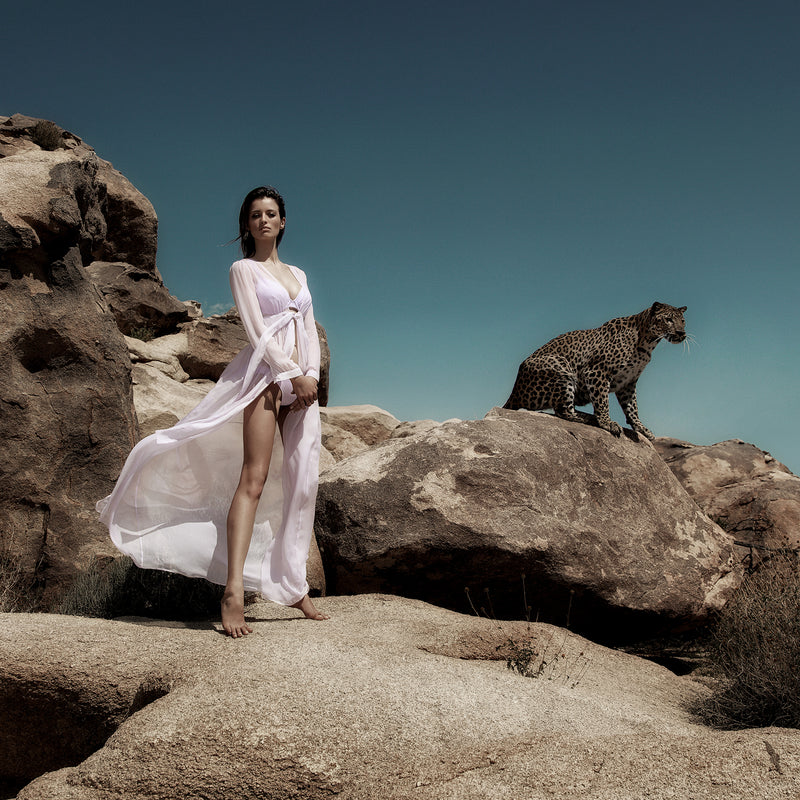 a cheetah and a woman in a lavender dress and bikini standing in the desert of palm springs 