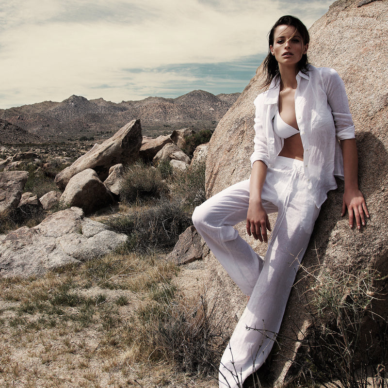 woman wearing a white bikini, linen shirt and pants in the desert of palm springs